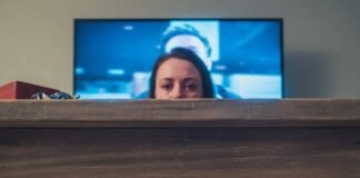 Romantic Movies That’ll Melt Even the Coldest Heart Person crying under a coffee table, feet and popcorn visible.