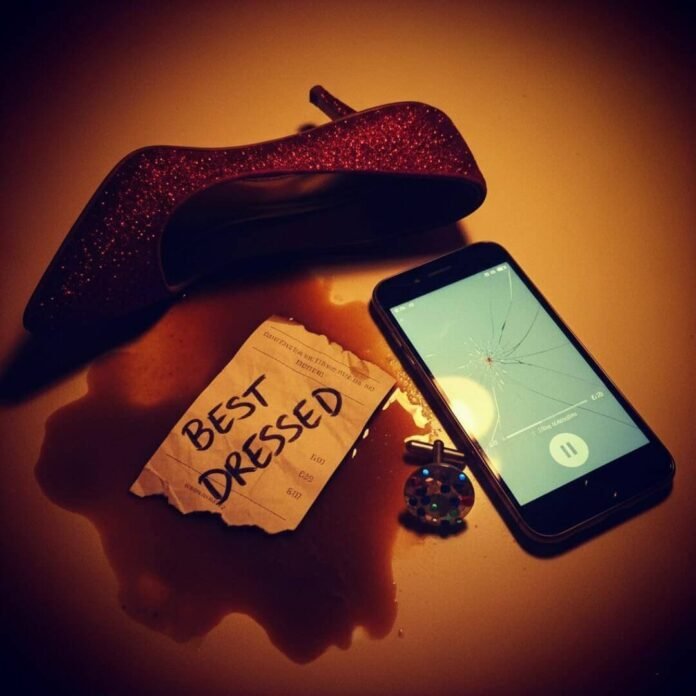 Ruby stiletto, betting slip, and cracked phone in a turmeric orange and violet palette.